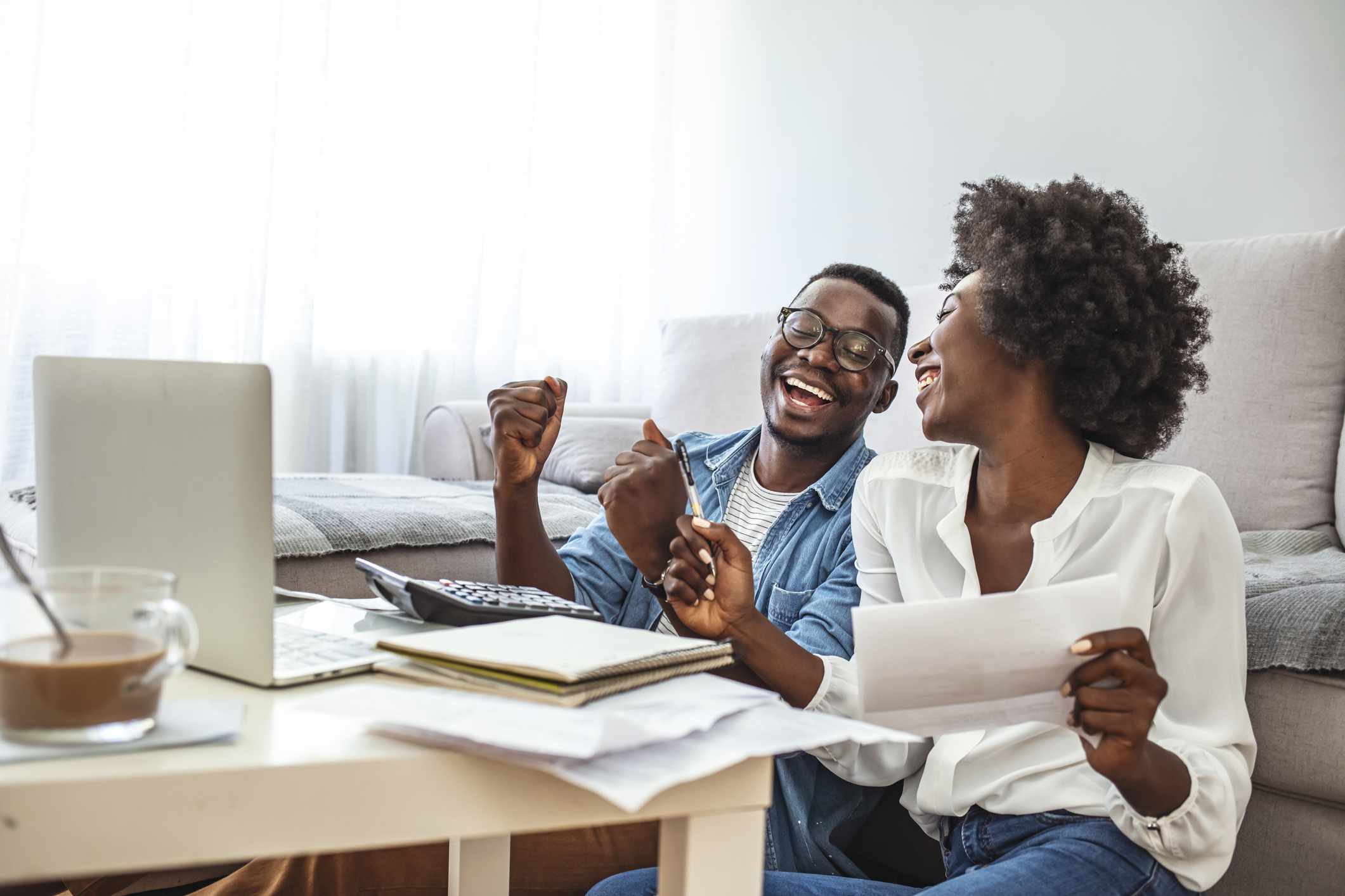 Happy couple going over finances with a laptop and calculator