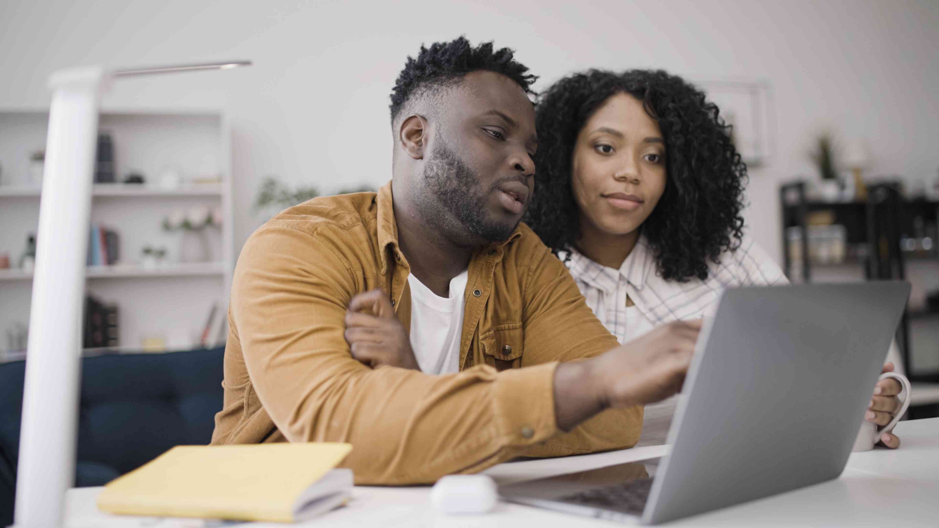 Young couple at home looking together at their laptop at their kitchen table