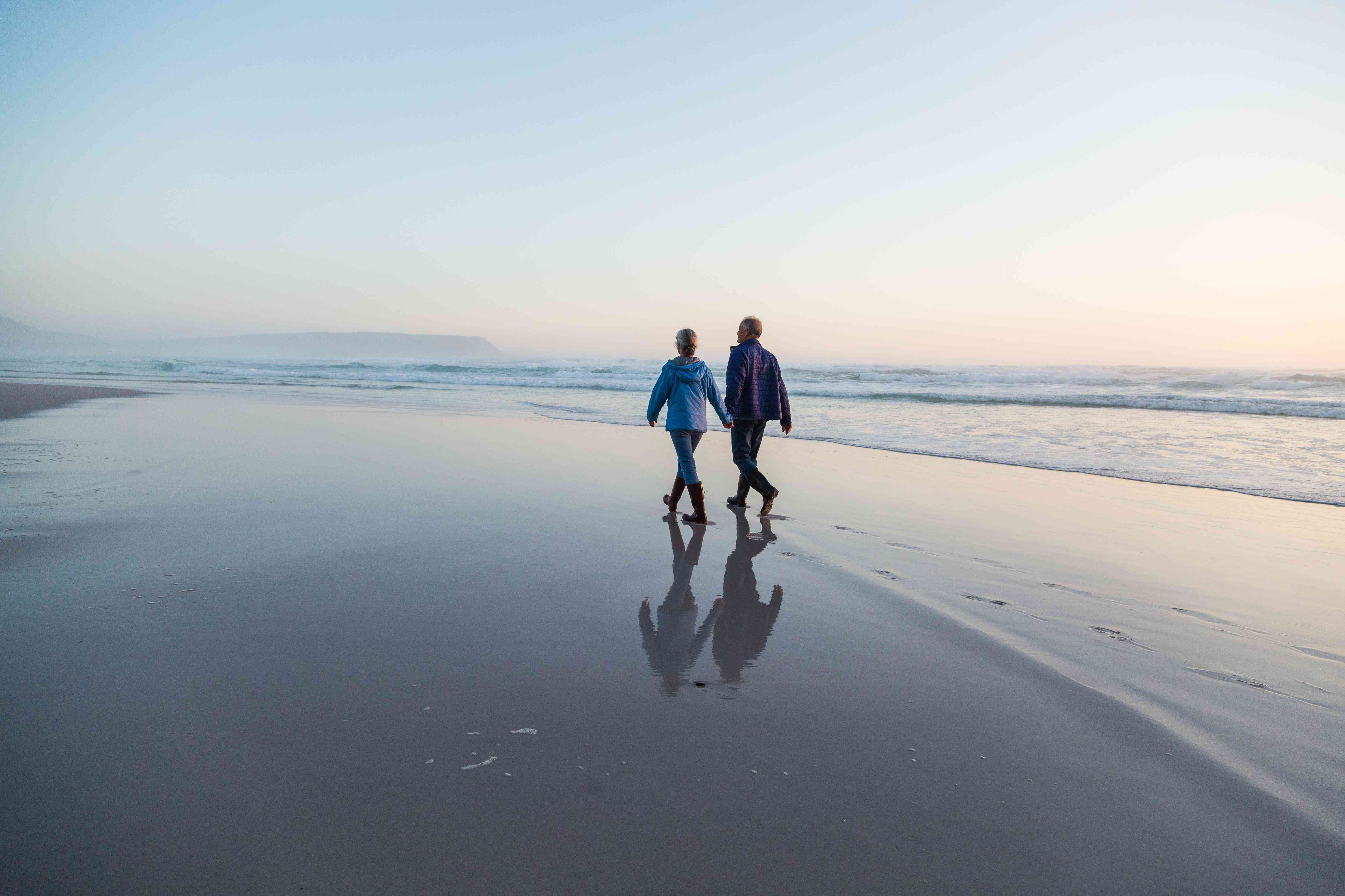 Two older adults holding hands on the beach