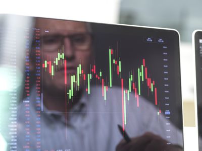 The reflection of an derivative investor appears on a computer monitor showing the price movement of the underlying stocks they are following.