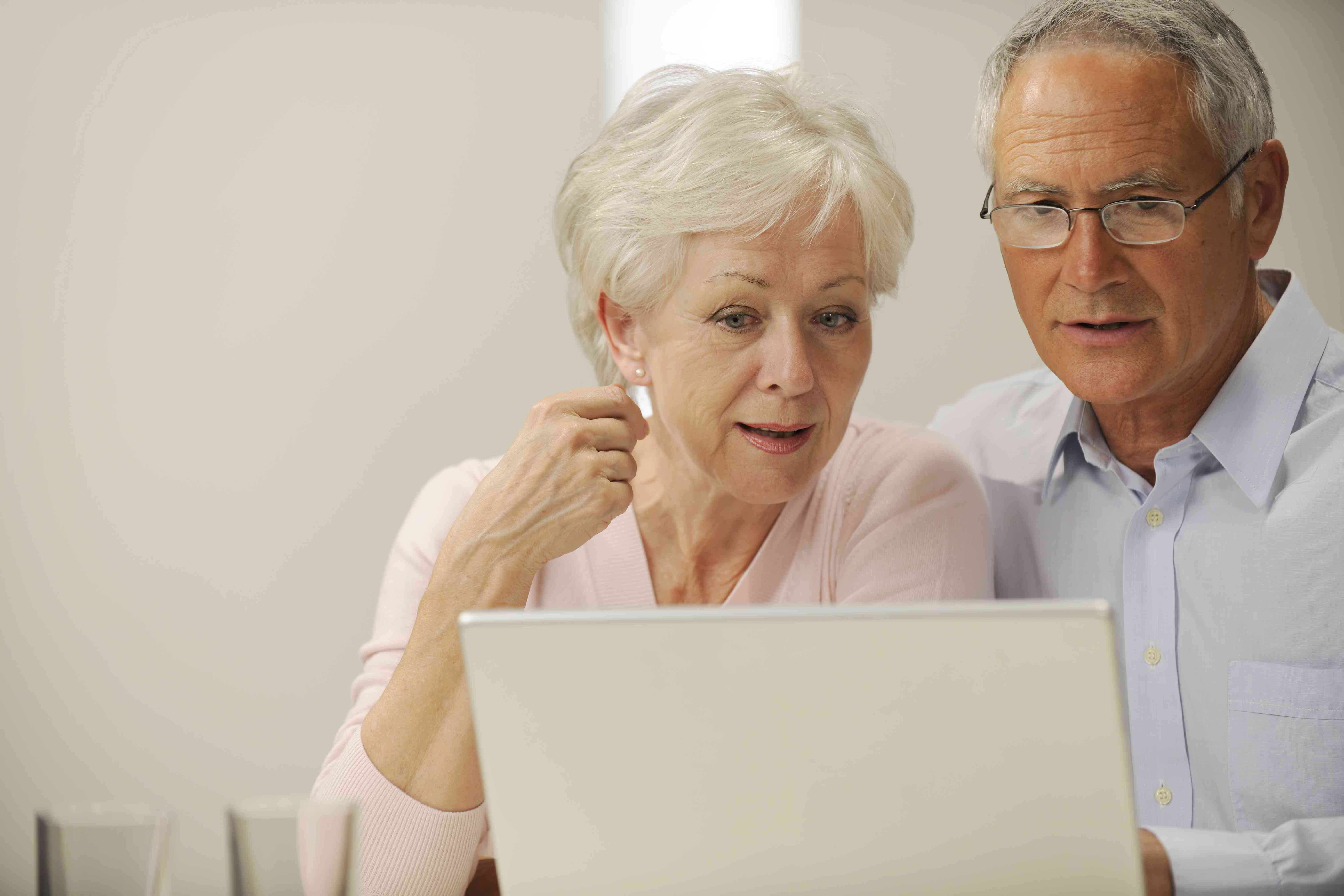 Older couple at home, looking together at a tablet screen