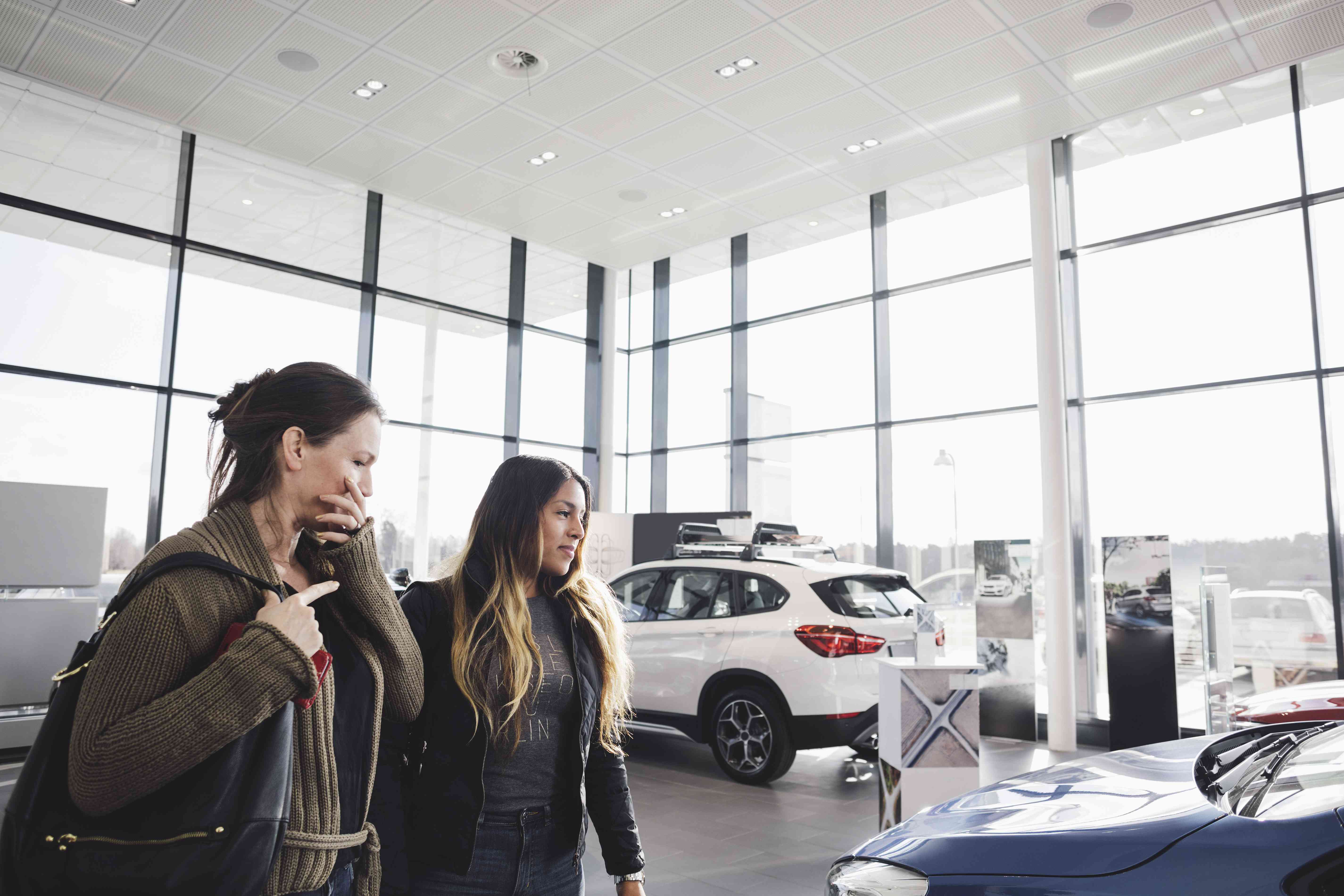 Two women visit a car showroom.