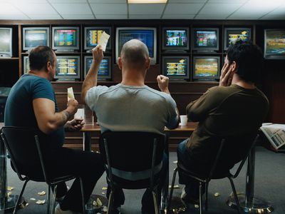 Three men in a betting shop with TVs showing various live betting events