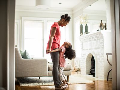 A woman and a young girl hug each other in a home.