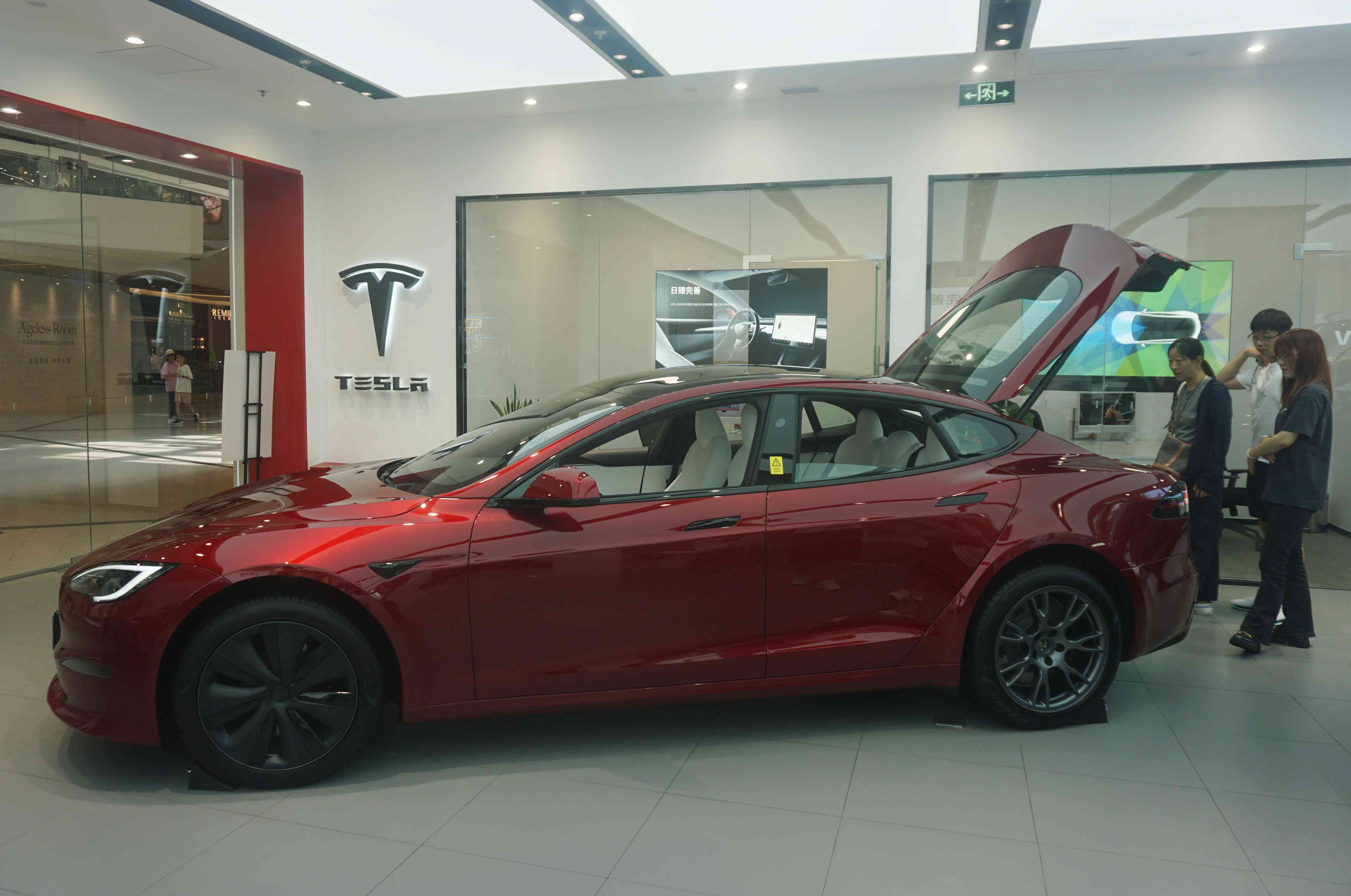 People check out a Tesla sedan in a dealership in Hangzhou city in east China's Zhejiang province