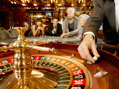 Close up of roulette wheel in a fancy casino with people betting in the background