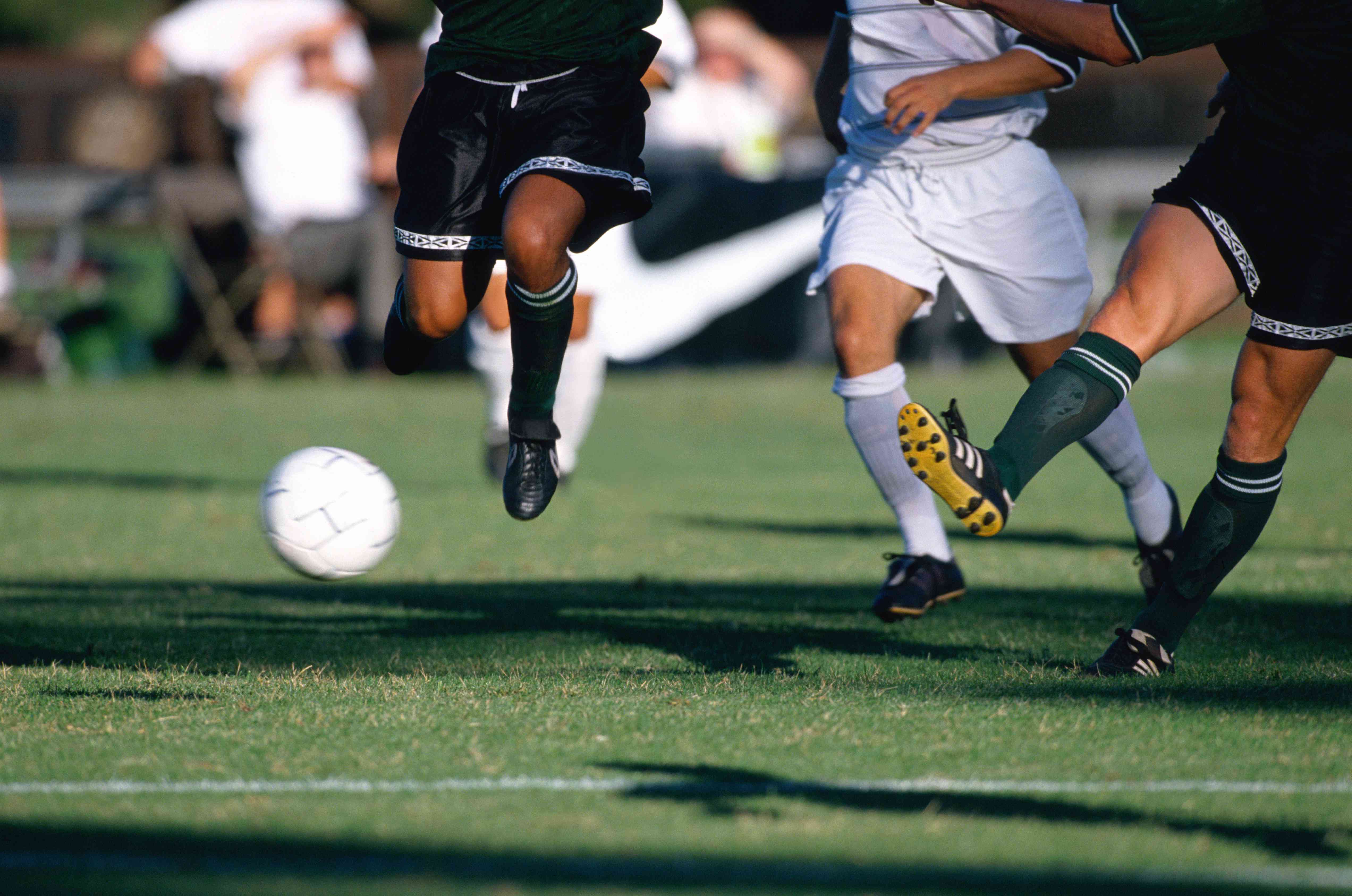 College soccer players chasing after a soccer ball during a game