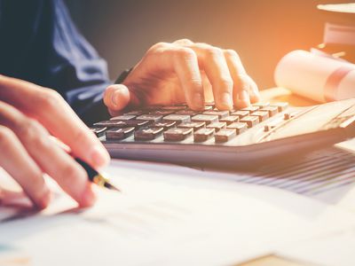 Close-up of a businessman's hands with a pen, papers, and a calculator