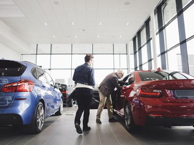 Senior man and woman examining car at showroom