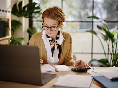 older woman working from her desk, looking at paperwork