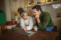 A couple uses a laptop to shop online.