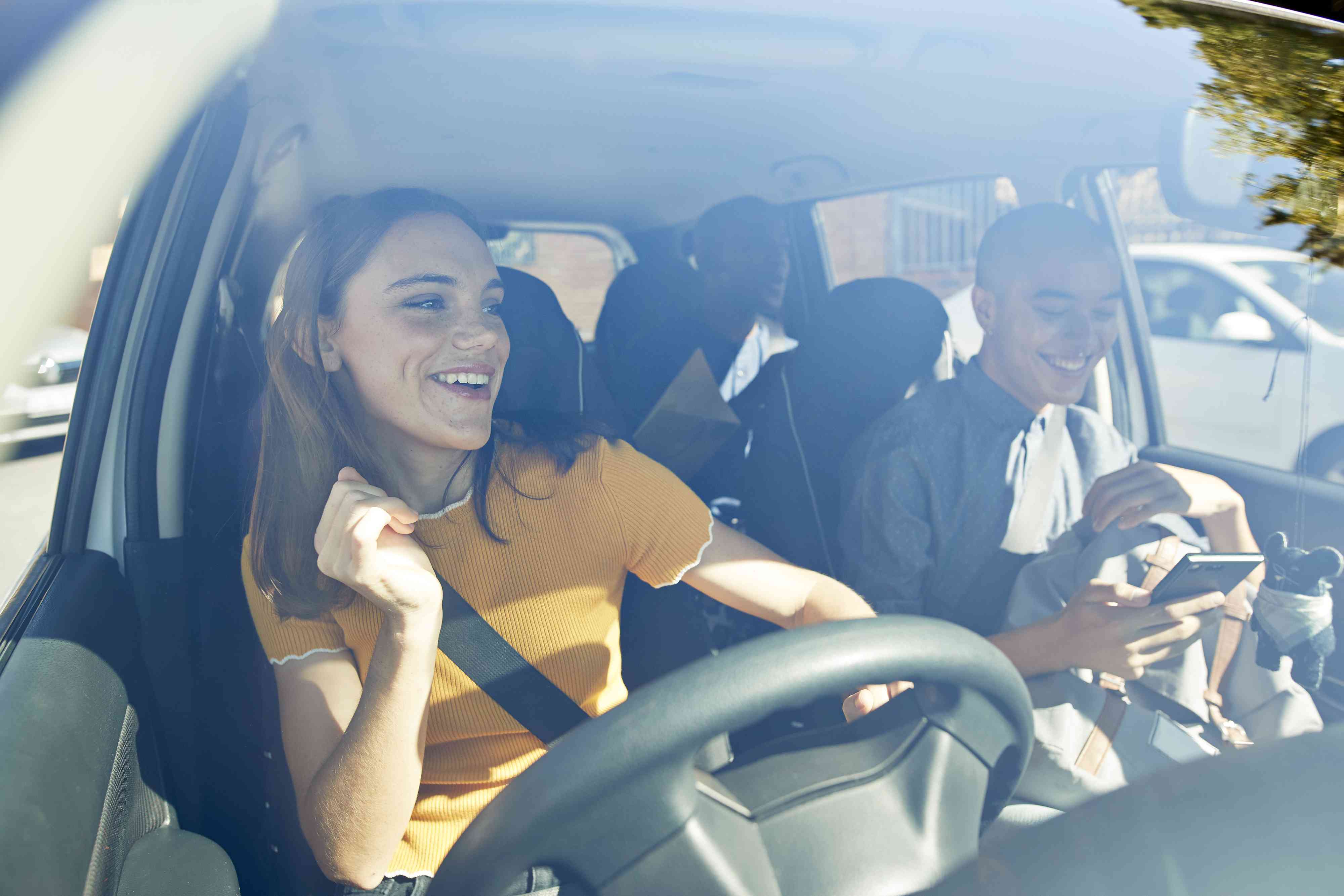 Happy young woman dancing with friends in car