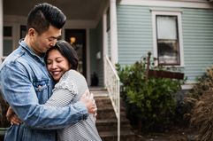 A young couple in front of a home