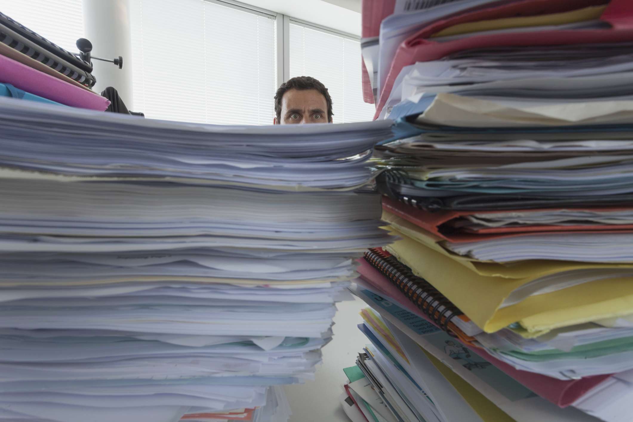 Man surrounded by piles of files in office