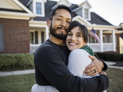 Husband and wife embracing in front of home