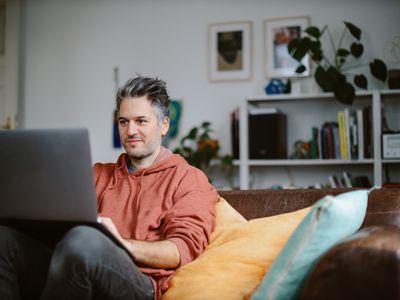 Man working on a laptop on his couch at home