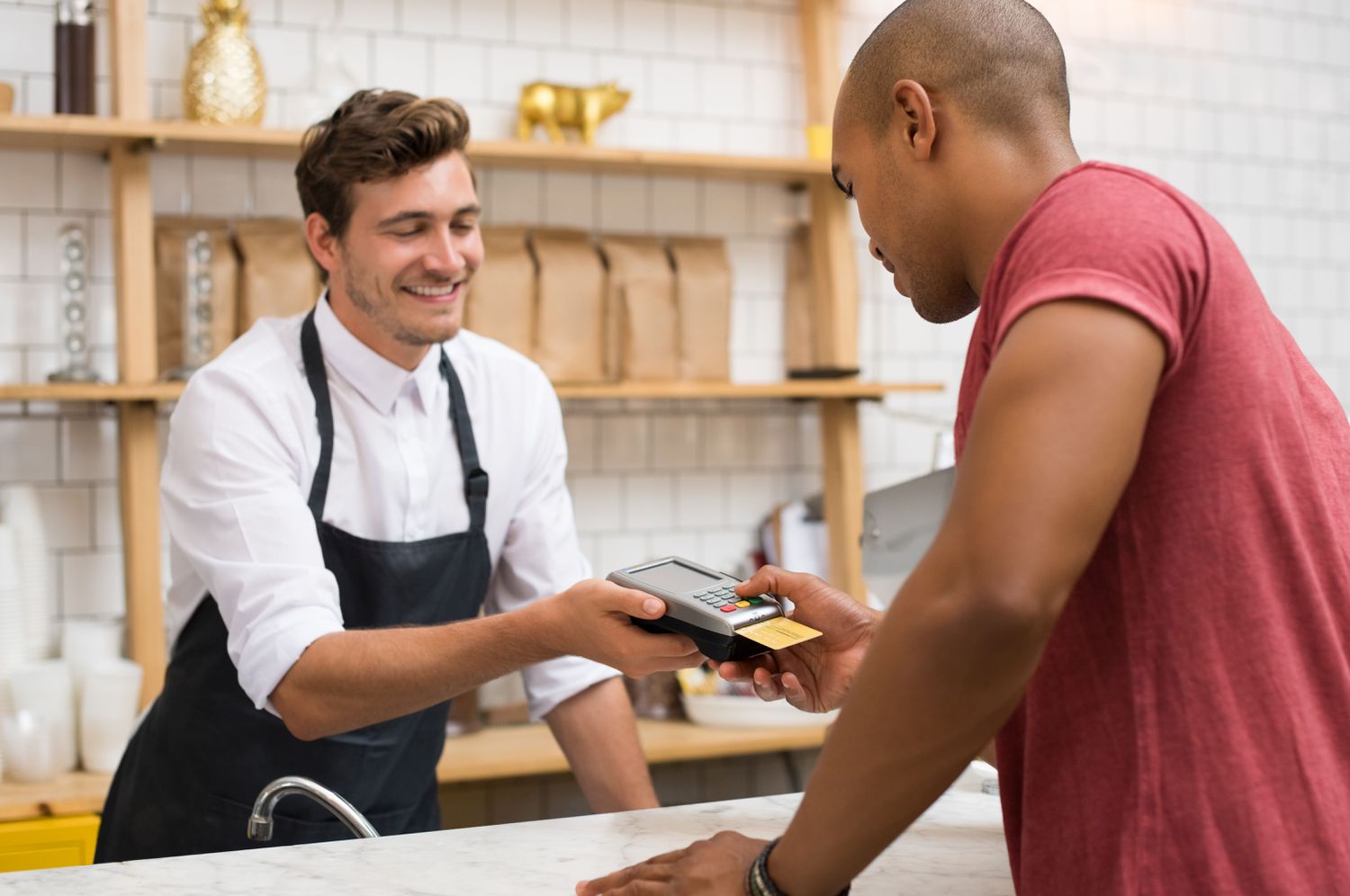 Person paying for something at a coffee shop using a credit card inserted into a credit card reader