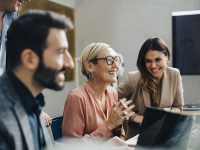 Three employees convene in a conference room.