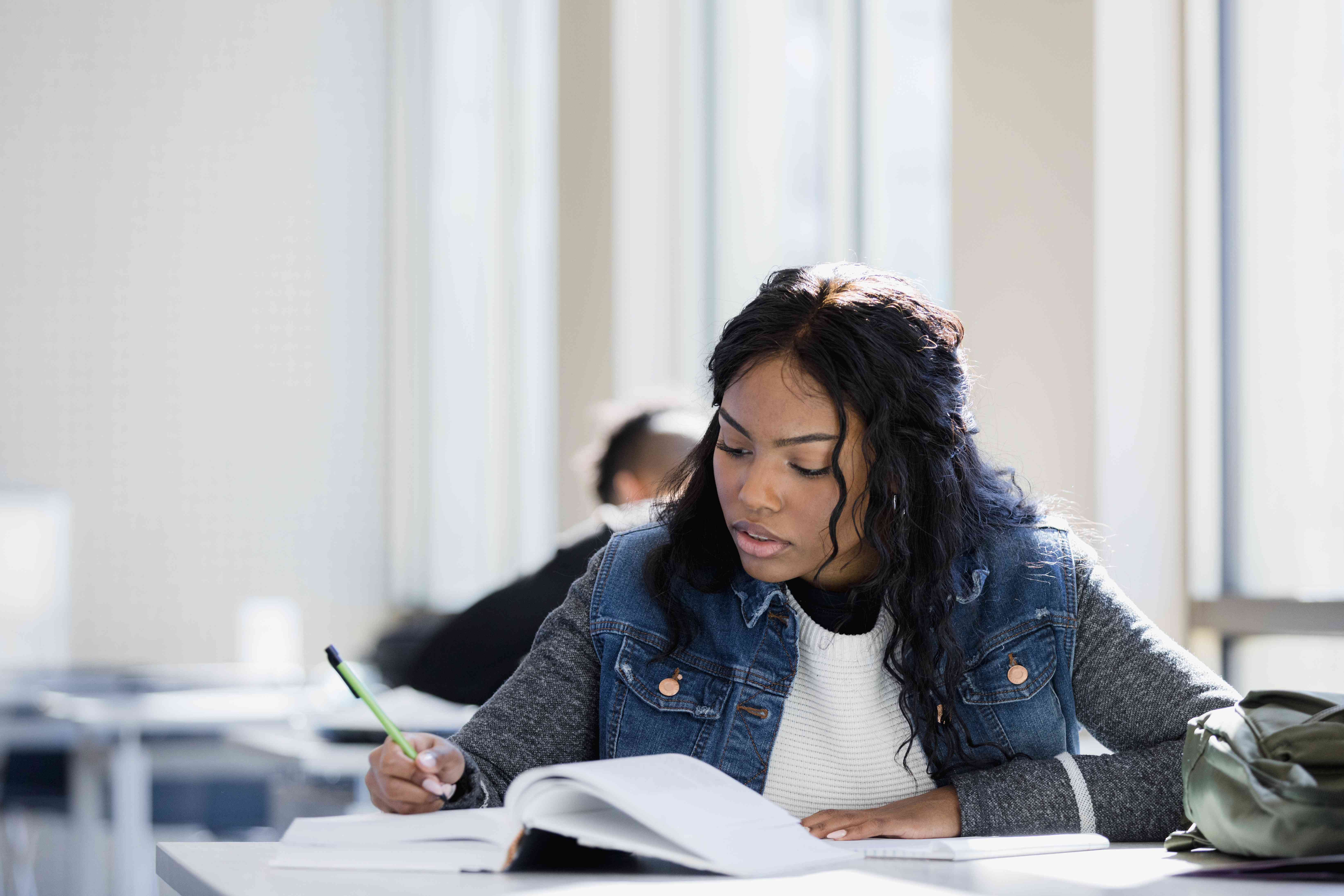 Student concentrates on studying whether she should consolidate her student loans.