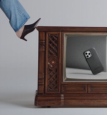 woman kicking old TV displaying black Defender Series case