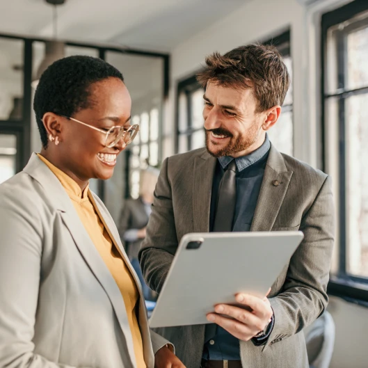 two people in business attire standing in an office and talking