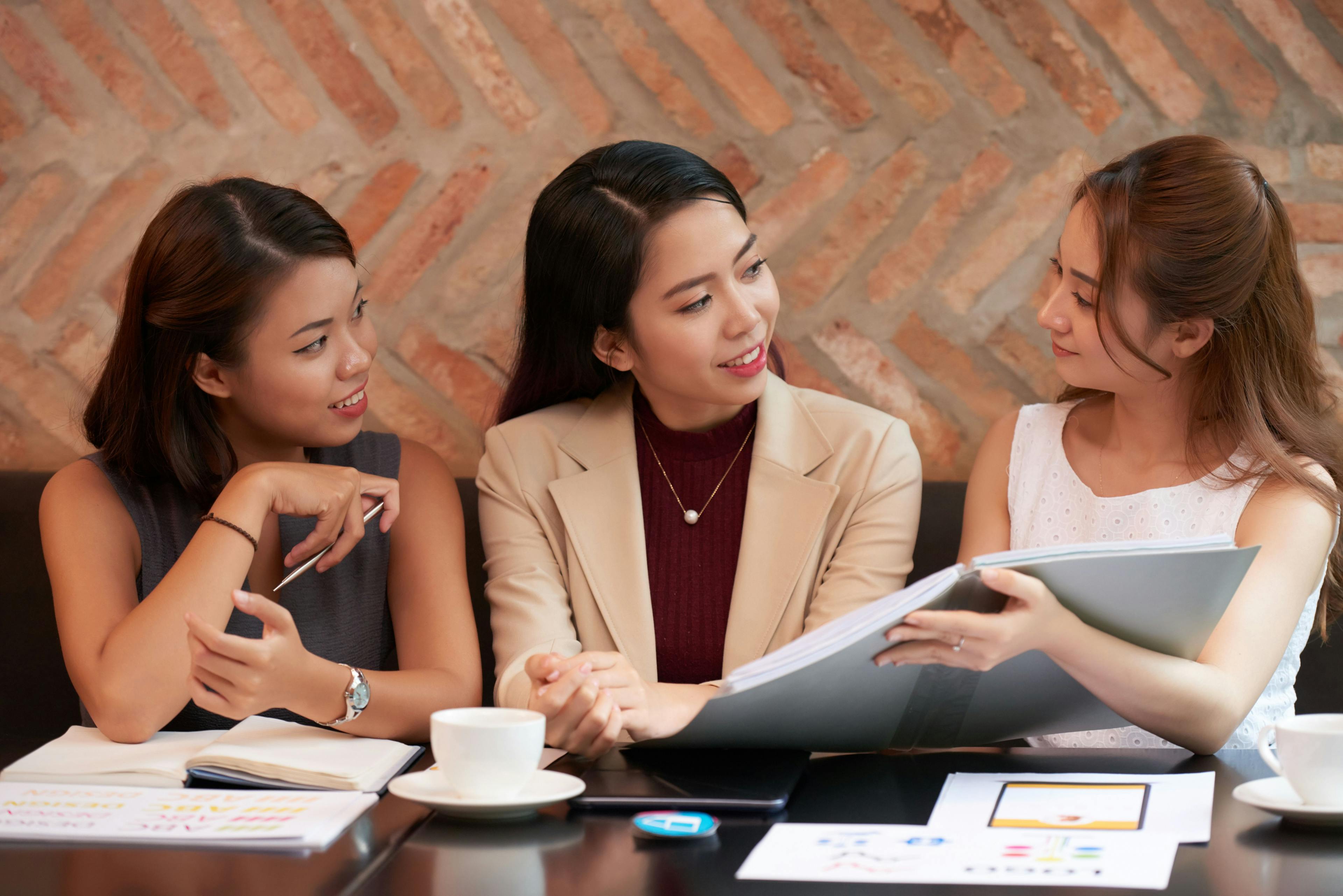 Three businesswomen discussing ideas and reviewing documents at a search engine marketing agency.