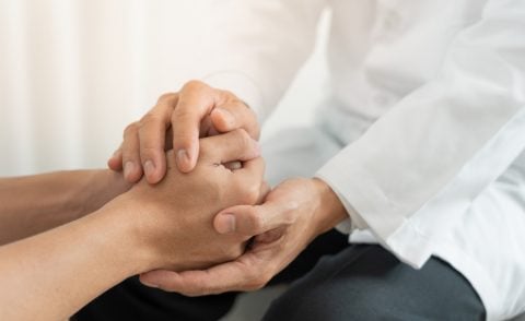 Man in a white coat holding another person's hands