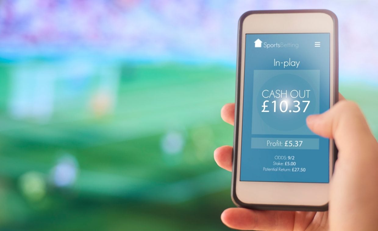 person holding phone with online betting app on screen