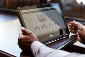 Close up shot of man‘s hands using Dell convertible laptop as tablet in café restaurant setting. Screen shows charts.