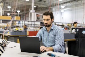 Man sitting at workstation in commercial manufacturing plant.