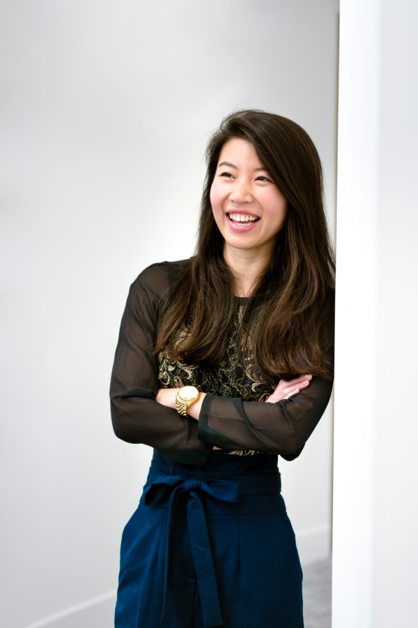 An employee smiling and leaning against a wall.