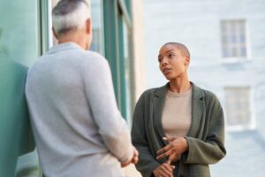 A man and a woman standing in front of a building talking to each other