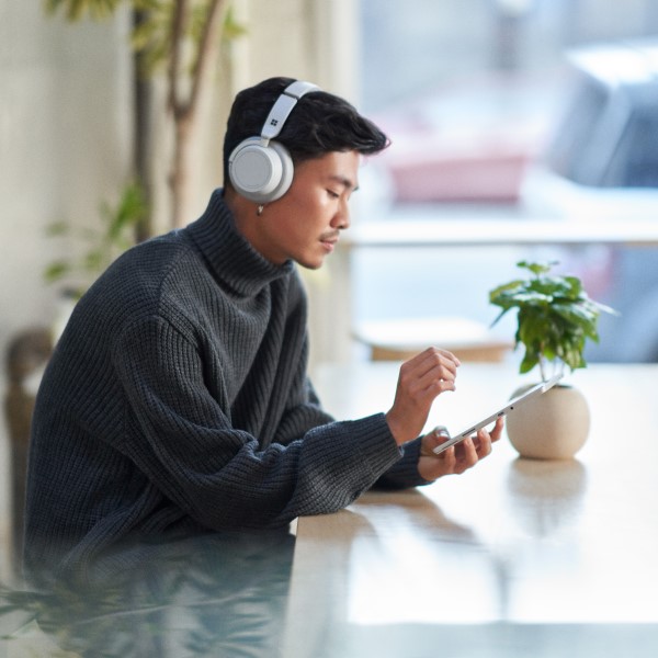 Customer using a tablet while wearing headphones and working securely remote from a café.