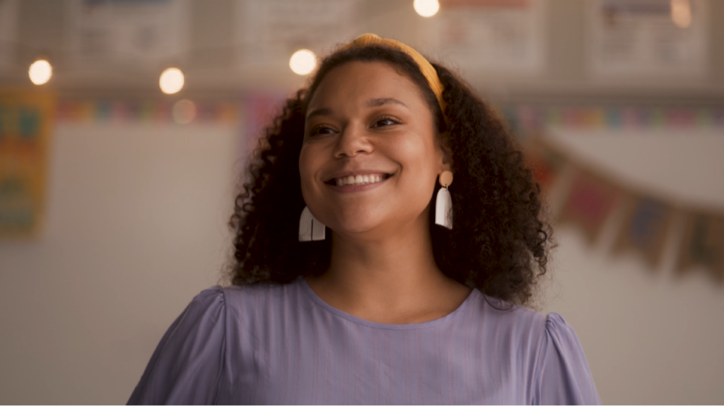 A female teacher smiling while looking at her classroom.