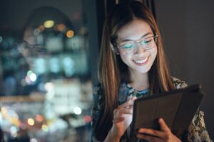 Young woman uses her digital tablet at night.