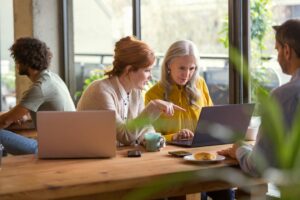 two women collaborating over laptops