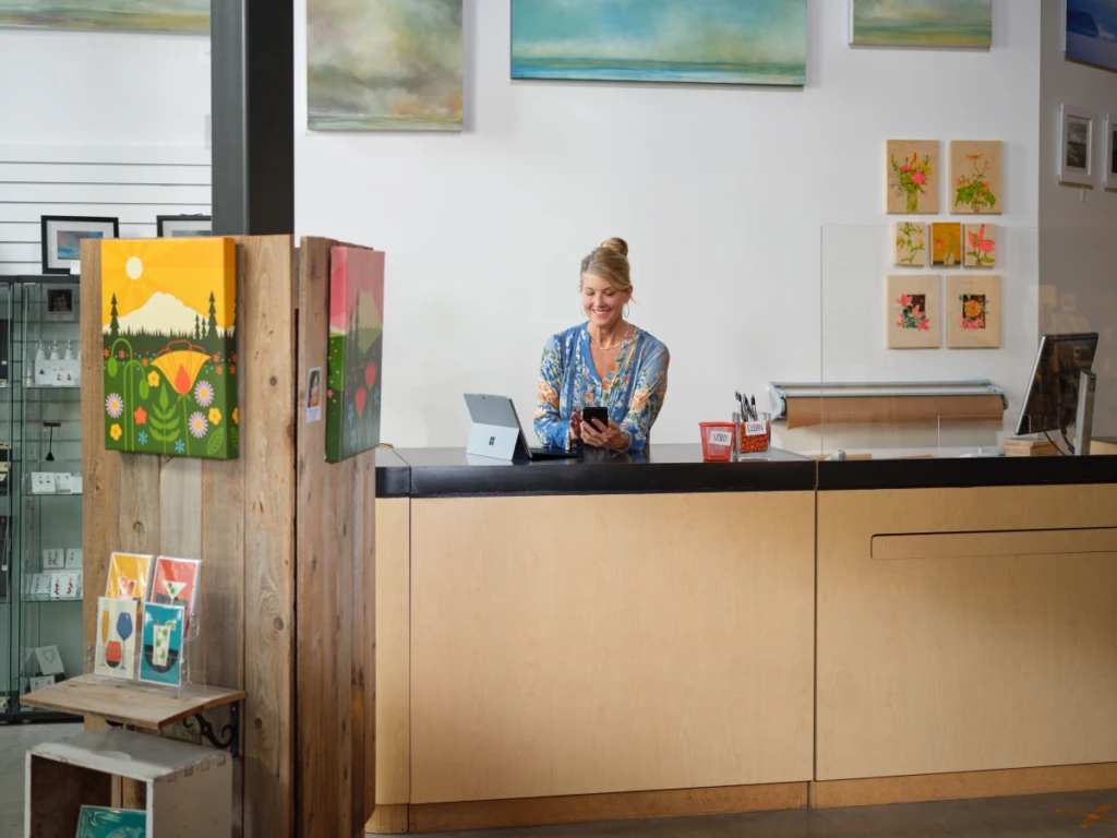 Retail shop owner working on Microsoft 365 Business Premium a mobile phone and a Surface.