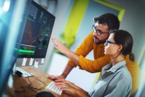 a man and a woman working together in front of a computer.