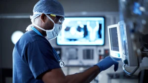 Doctor with protective gear working on a monitor