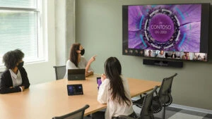 Team sitting around a board room table, engaged in a teams call on a large video wall.