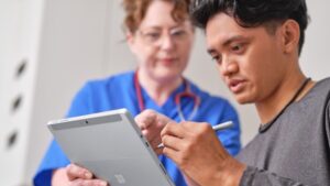 Man signing tablet with nurse pointing to a specific spot