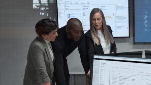 Three people in suits are looking at a computer screen.