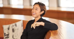 A woman sits on a bench smiling.