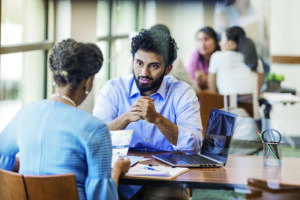 Customer reviews a bank brochure, while bank employee explains the loan application process.