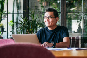 Smiling Chinese man working on laptop at home