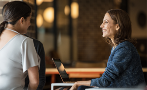 Image of two firstline workers meeting in a meeting room. One has her laptop open.