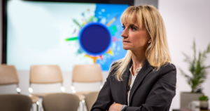 A woman reflects inside a conference room.