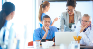 Image of doctors and nurses surrounding a laptop.