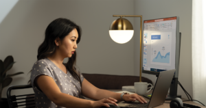 An image of a woman working at her home office on a Lenovo ThinkPad Yoga connected to an external monitor.