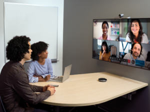 Two coworkers in conference room on a Microsoft Teams call with four other people